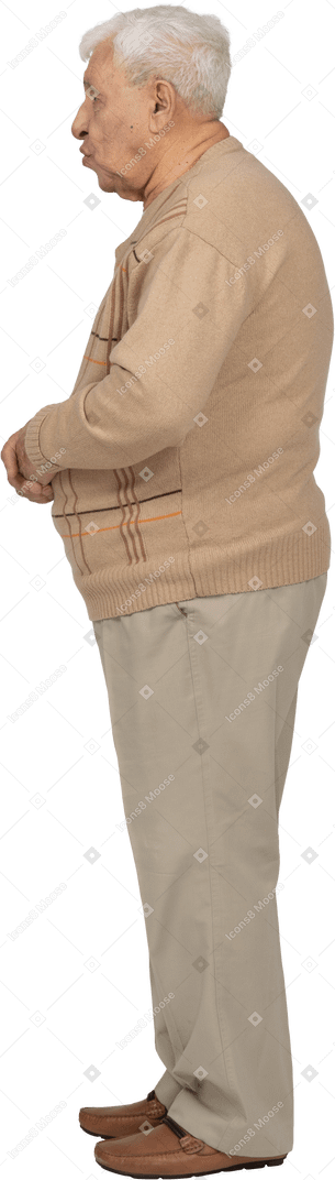 Vue latérale d'un vieil homme en vêtements décontractés debout avec les bras croisés et soufflant un baiser