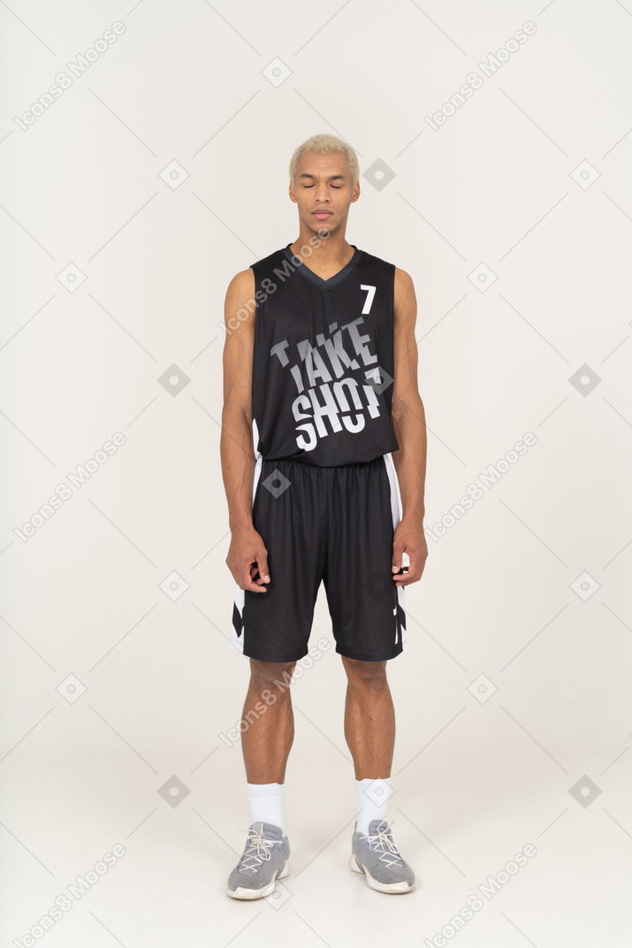 Front view of a young male basketball player standing with his eyes closed