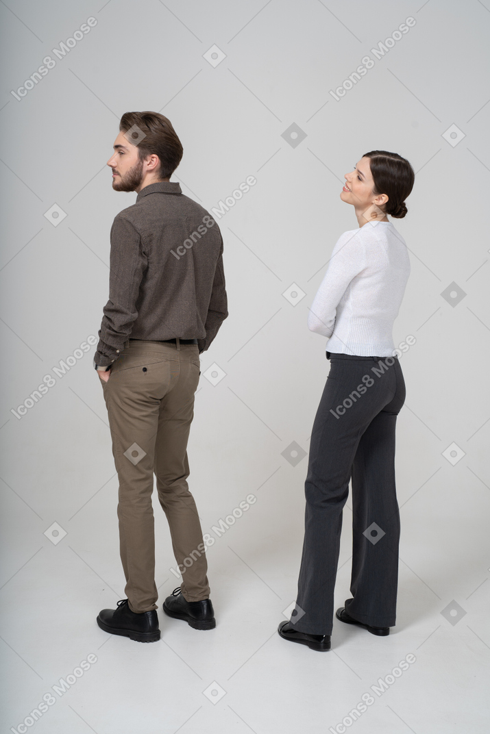 Three-quarter back view of a man in casual clothing putting hands in pockets and a pleased young woman