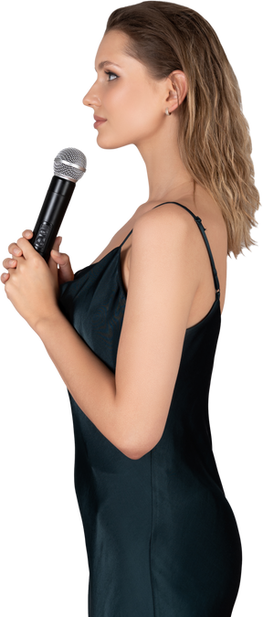 Side view of a young woman in night gown holding a microphone