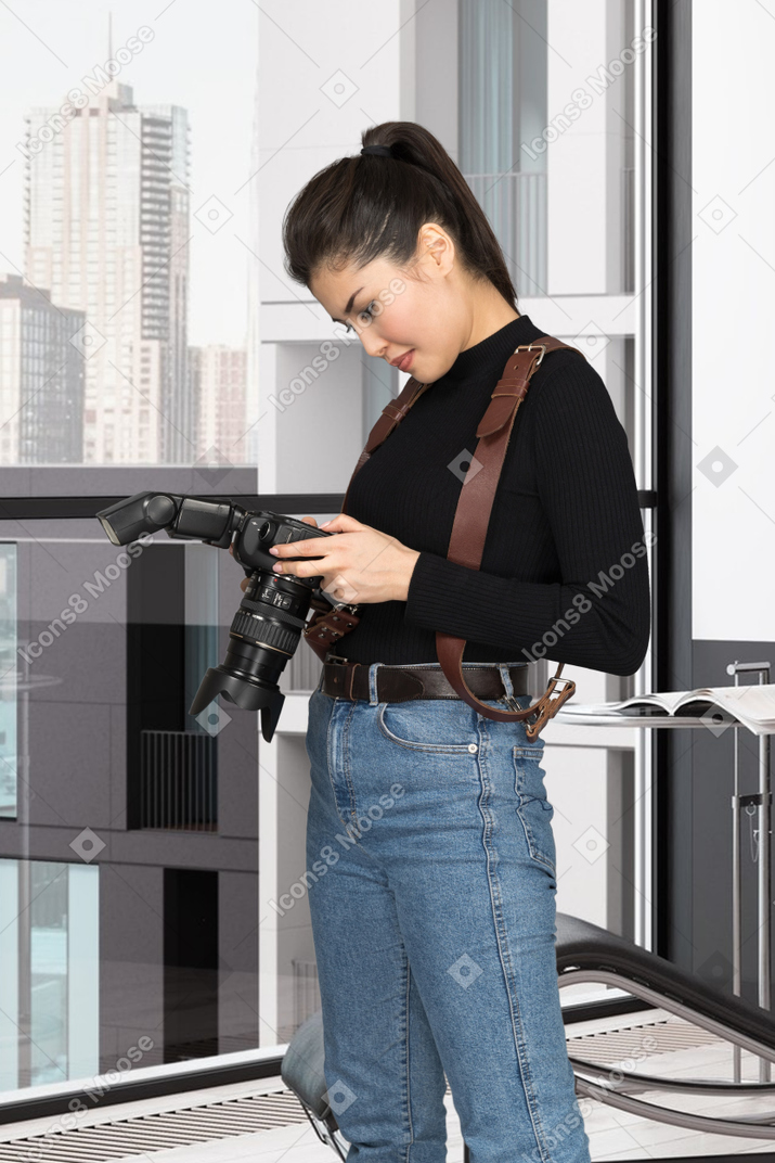 A woman in a black shirt and jeans holding a camera