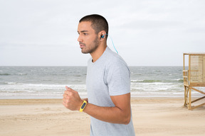 A man running on the beach with earphones