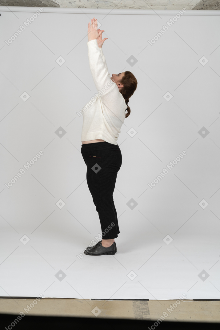 Vista lateral de una mujer regordeta en ropa casual con los brazos levantados