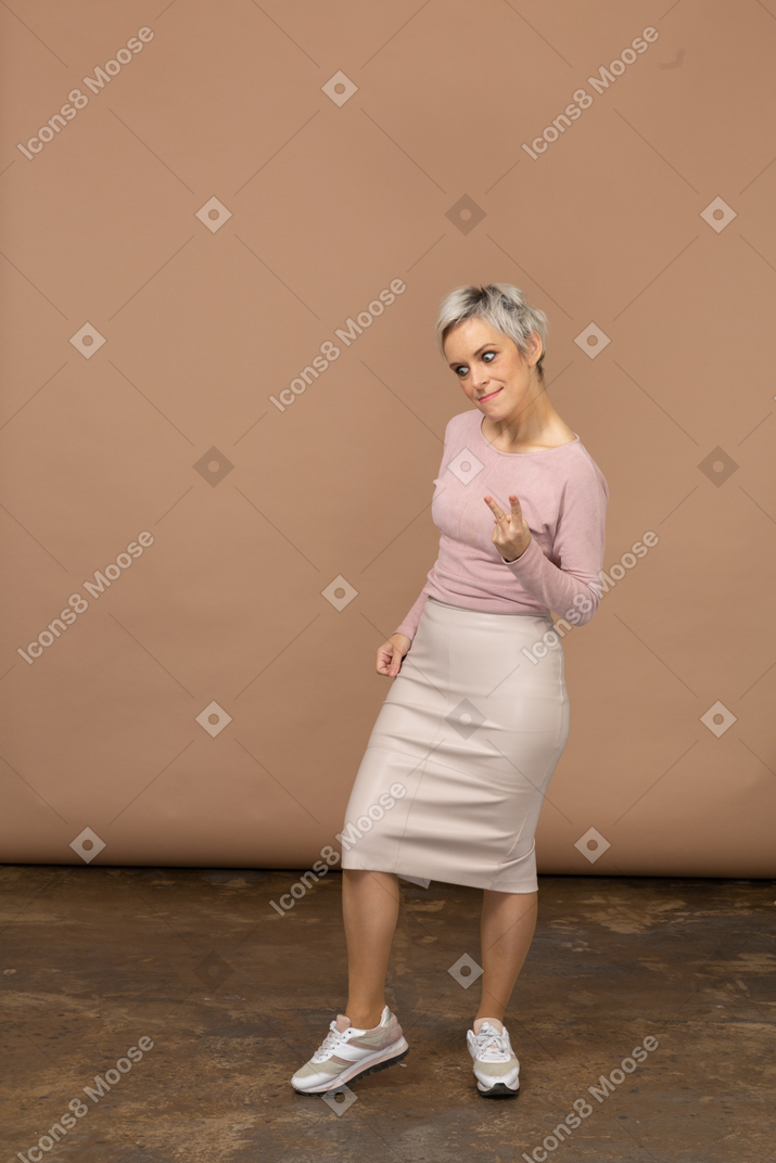 Vista frontal de uma mulher emocional em roupas casuais, mostrando o gesto de rocha