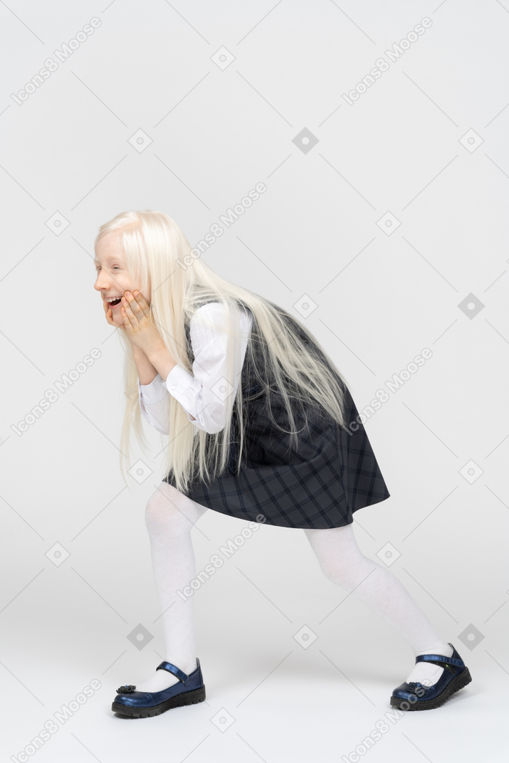 Schoolgirl holding her face with both hands and laughing
