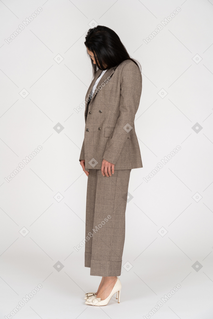 Vista de tres cuartos de una señorita en traje marrón mirando hacia abajo