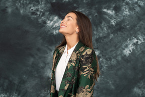 Dreiviertelansicht einer frau in grüner japanischer jacke, die mit geschlossenen augen weit lächelt