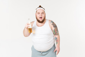 Ein dicker mann in sportkleidung hält eine flasche bier