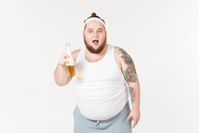 Um homem gordo no sportswear segurando uma garrafa de cerveja