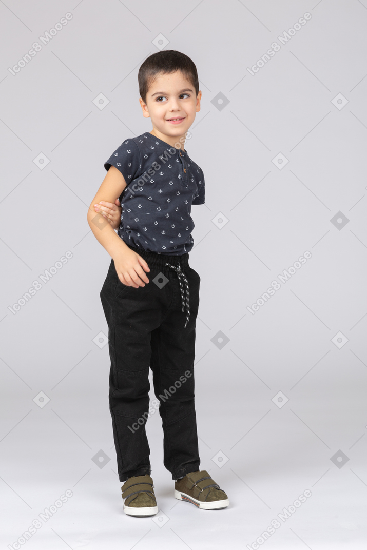 Front view of a happy boy in casual clothes posing with hand in pocket
