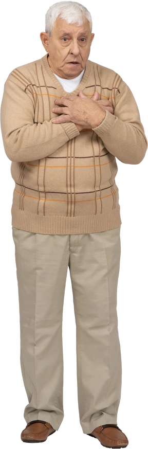 Front view of a scared old man in casual clothes standing with hands on chest
