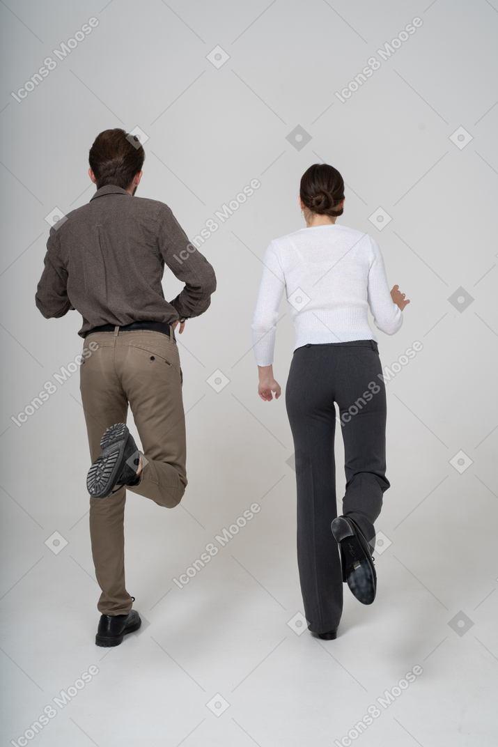 Vista traseira de um jovem casal com roupa de escritório levantando a perna