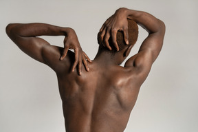 Back view of man touching shoulder and head