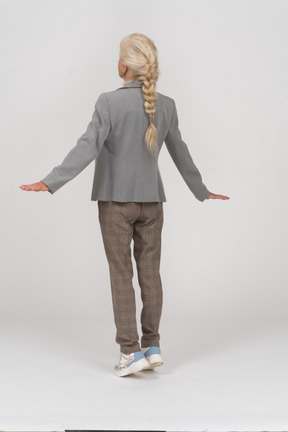 Back view of an old lady in suit standing on toes and outstretching arms