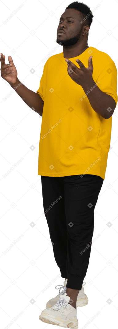 Vista de tres cuartos de un joven hombre de piel oscura gesticulando pensativo en camiseta amarilla