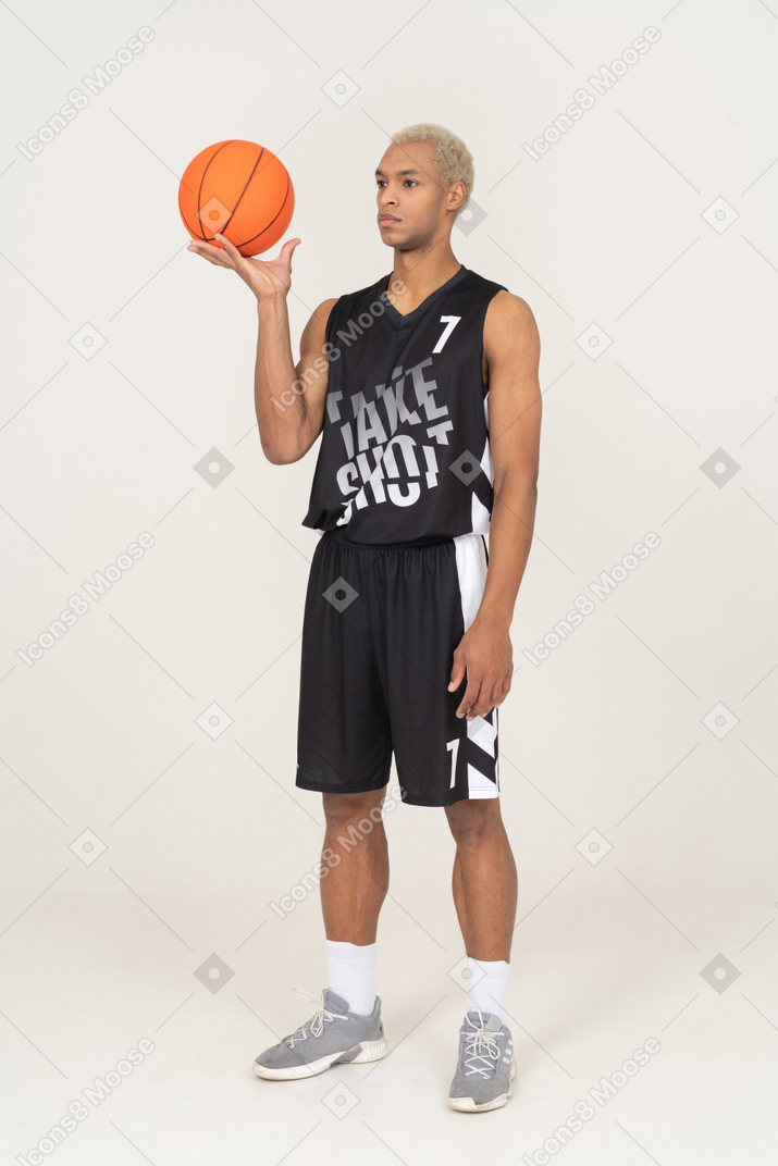 Three-quarter view of a young male basketball player holding a ball