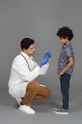 El doctor está listo para ponerle una inyección al niño.
