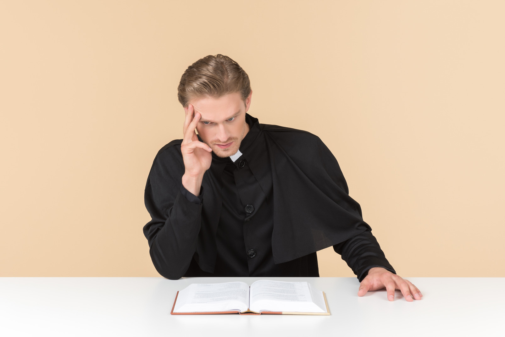Pensive catholic priest sitting in front of open bible