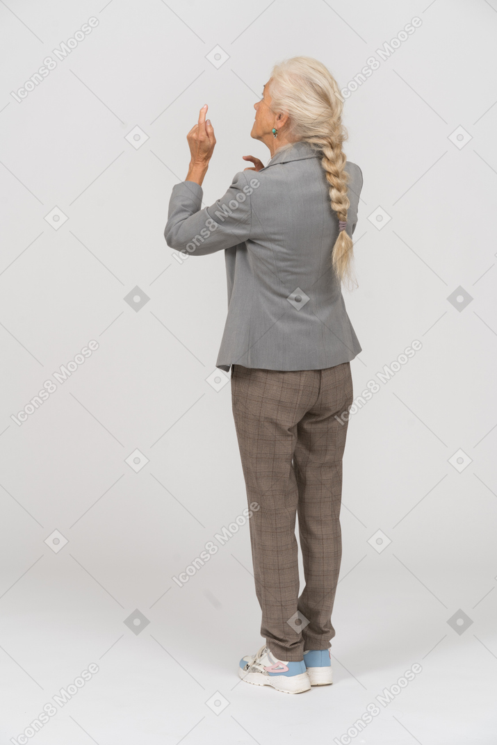 Vista trasera de una anciana en traje apuntando con los dedos