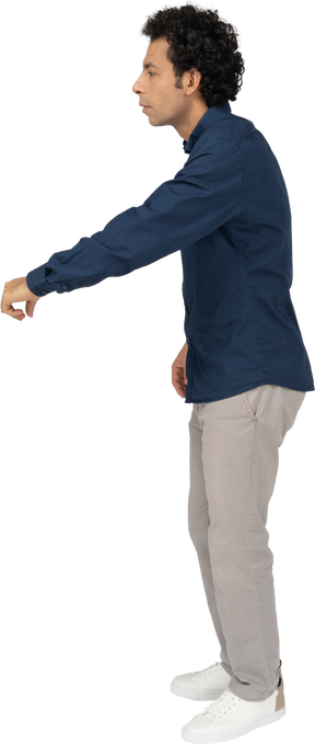 Side view of a man in casual clothes standing with outstretched arm
