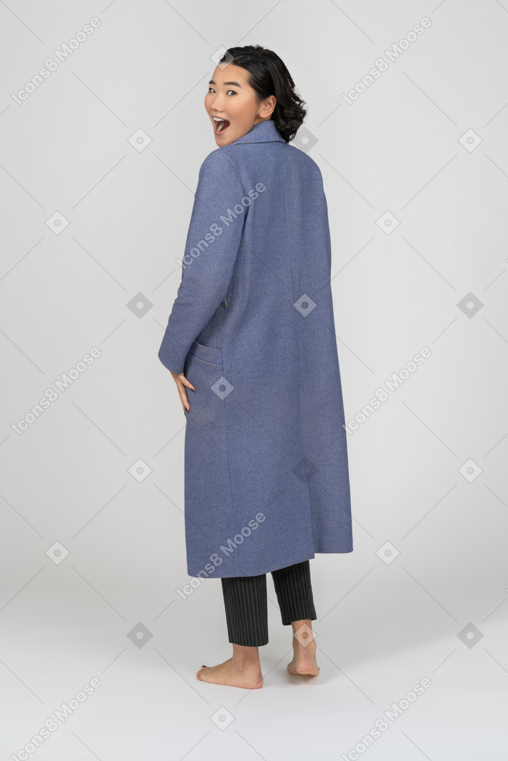 Vista posteriore di una donna sorridente in cappotto