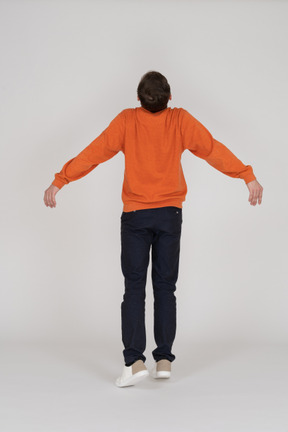 Junger mann im orange sweatshirt springen