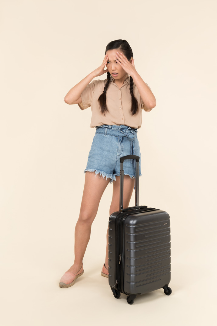 Worried young woman standing near the suitcase