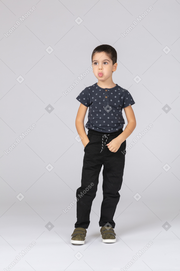 Front view of a cute boy posing with hand in pocket and showing tongue