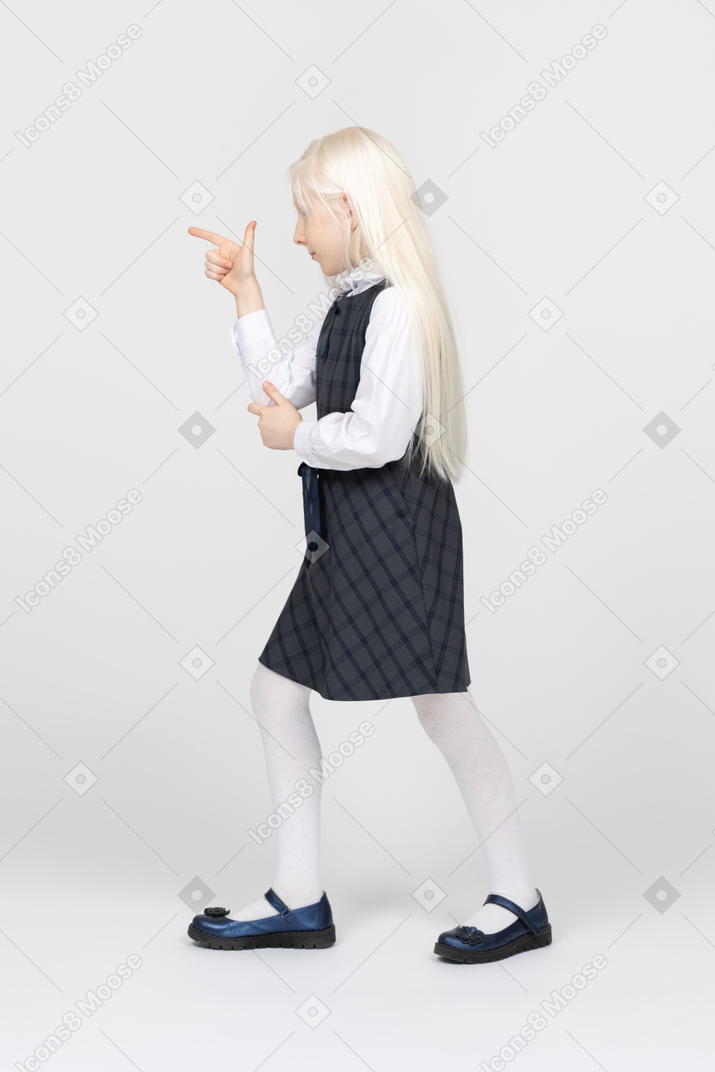 Side view of a schoolgirl making finger gun