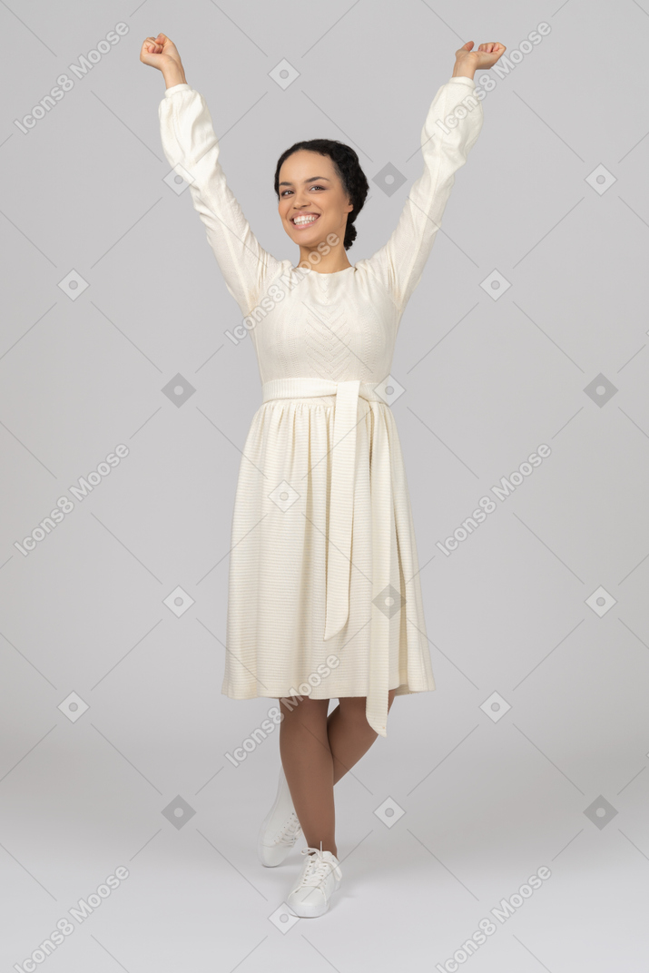 Excited young woman looking at camera with her hands in the air
