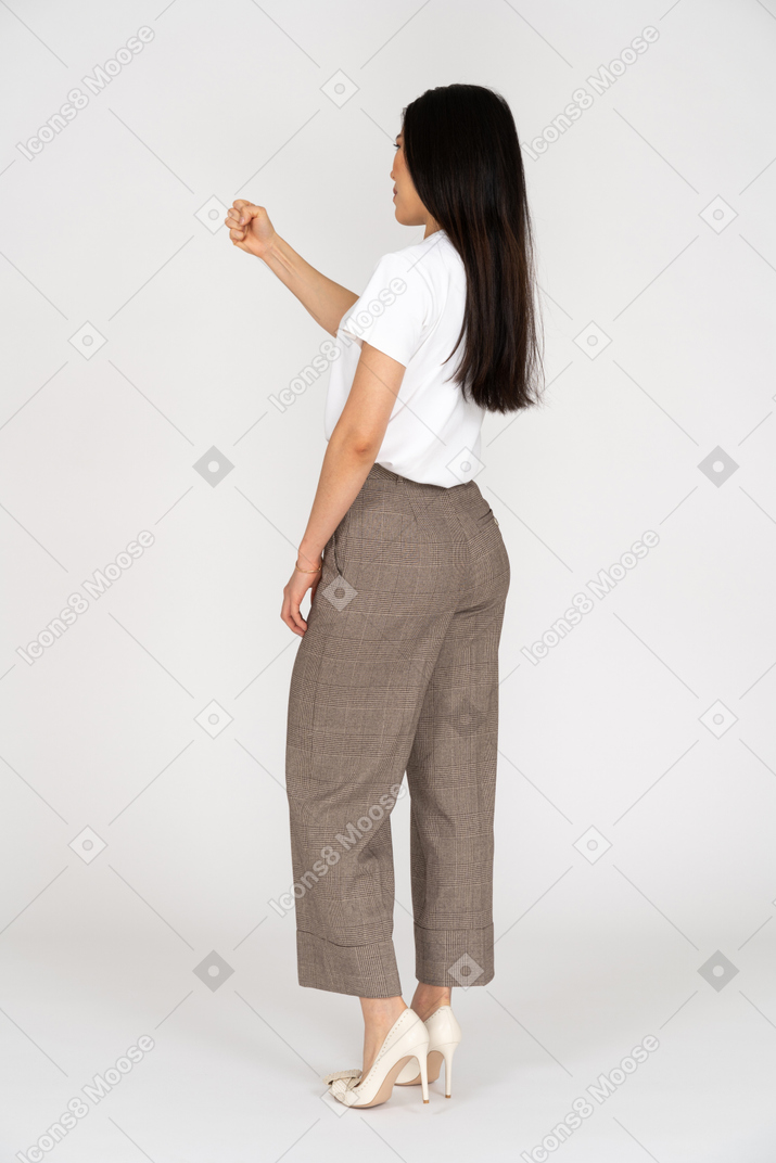 Three-quarter back view of a young woman in breeches clenching fist