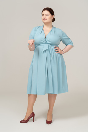 Вид спереди женщины в синем платье, указывая пальцем вниз