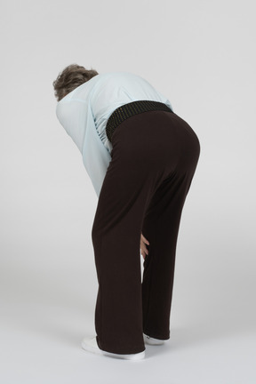 Three-quarter back view of old woman bending down
