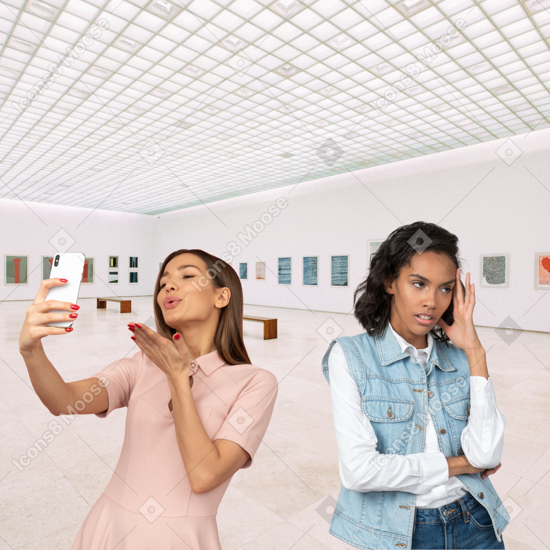 A woman annoyed at another woman taking selfies in museum