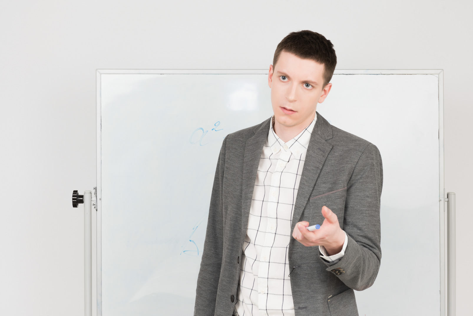 Young teacher standing at the whiteboard and pointing at something