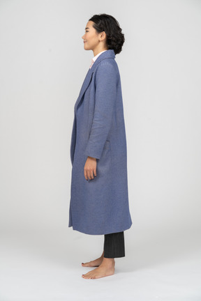 Vista lateral de una mujer sonriente con abrigo azul