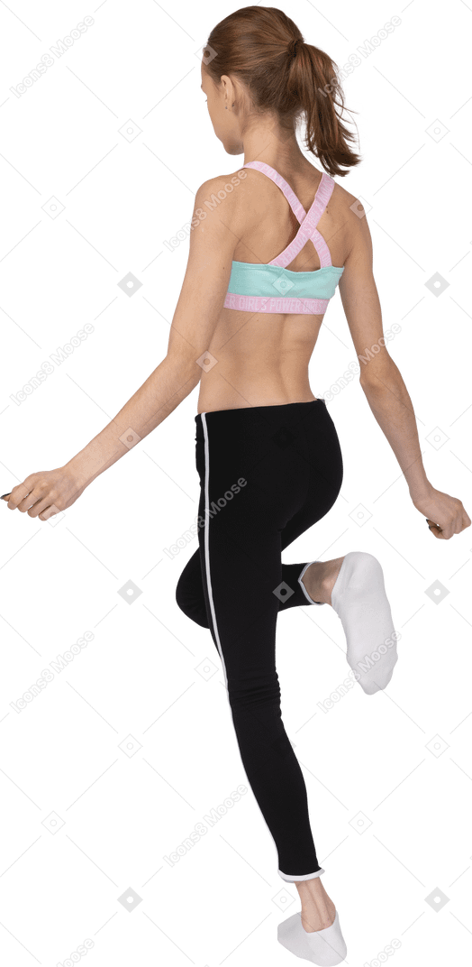 Three-quarter back view of a teen girl in sportswear raising leg