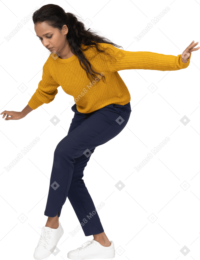 Side view of a girl in casual clothes posing on one leg with outstretched arms