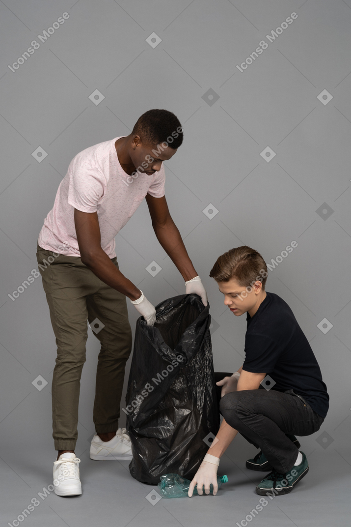 Young man picking up a plastic bottle