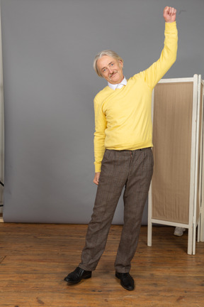 Front view of an old smiling man raising his hand
