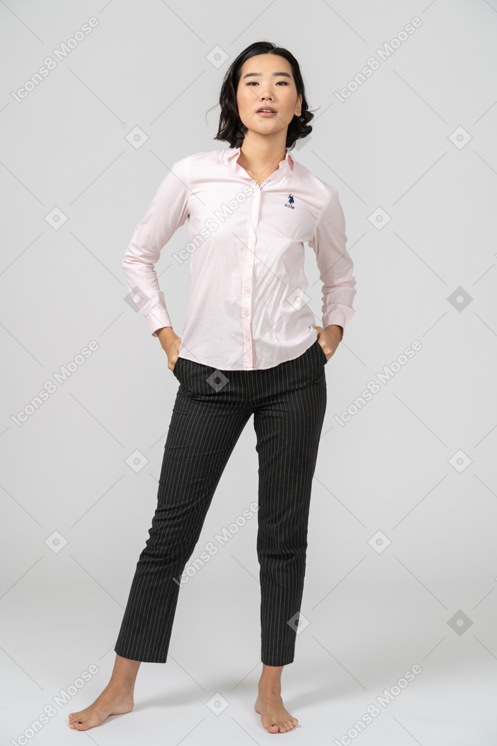 Mulher em roupas de escritório posando com as mãos nos bolsos
