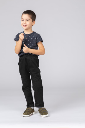 Vista frontal de um menino fofo em roupas casuais, mostrando o polegar