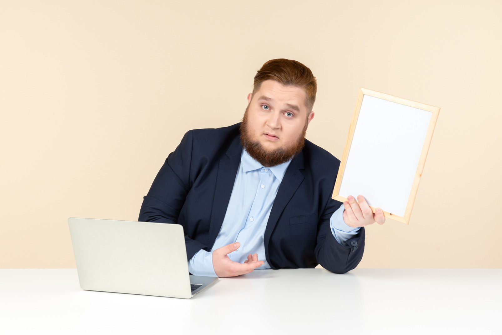 Young overweight man sitting at the desk and holding picture frame