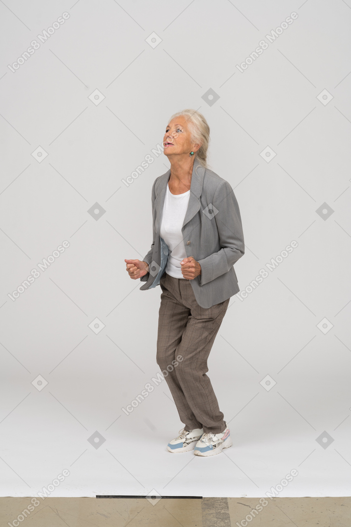 Vista laterale di una vecchia signora in completo che salta
