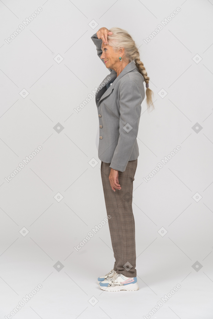 Side view of an old woman in suit touching forehead