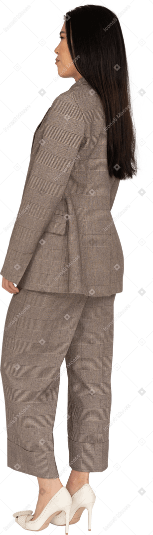 Три четверти сзади морщинистой молодой леди в коричневом деловом костюме