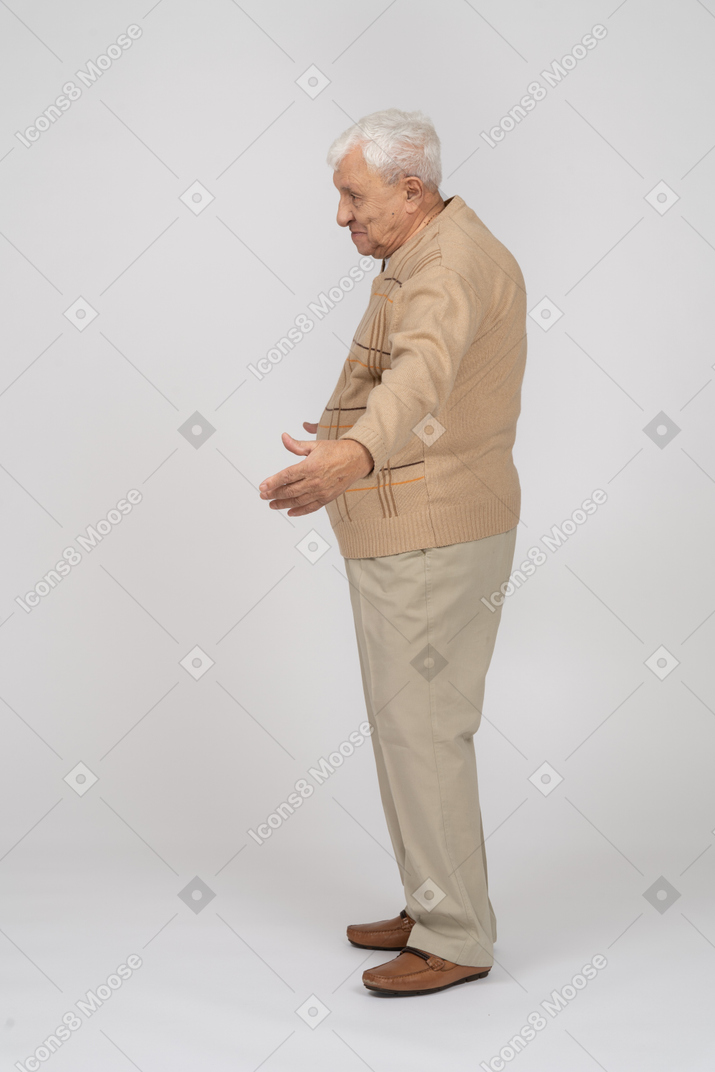 一位穿着休闲服的老人张开双臂站立的侧视图