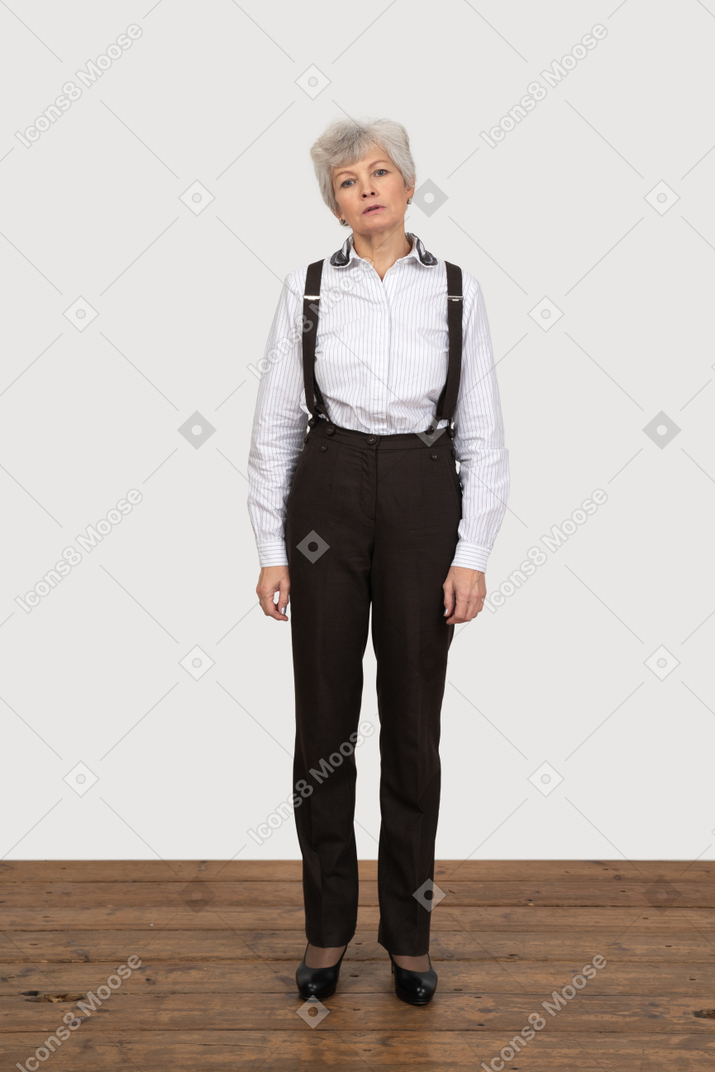 Vista frontale di una vecchia donna in abiti da ufficio in piedi ancora nella stanza