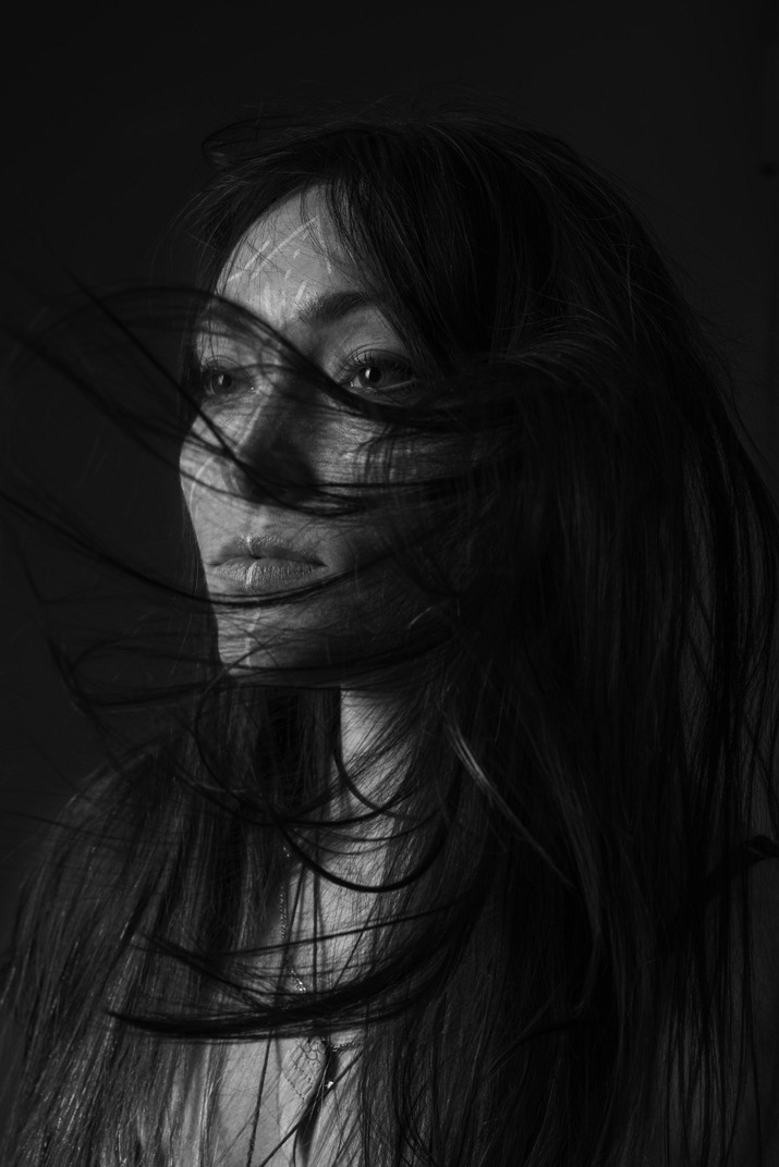 Three-quarter dark portrait of a young woman with messy hair