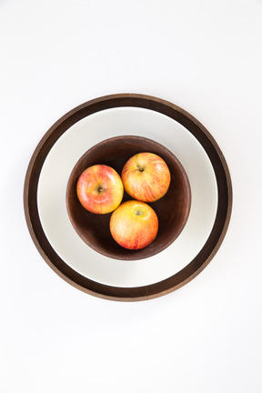 Apples in wooden plate on some plates